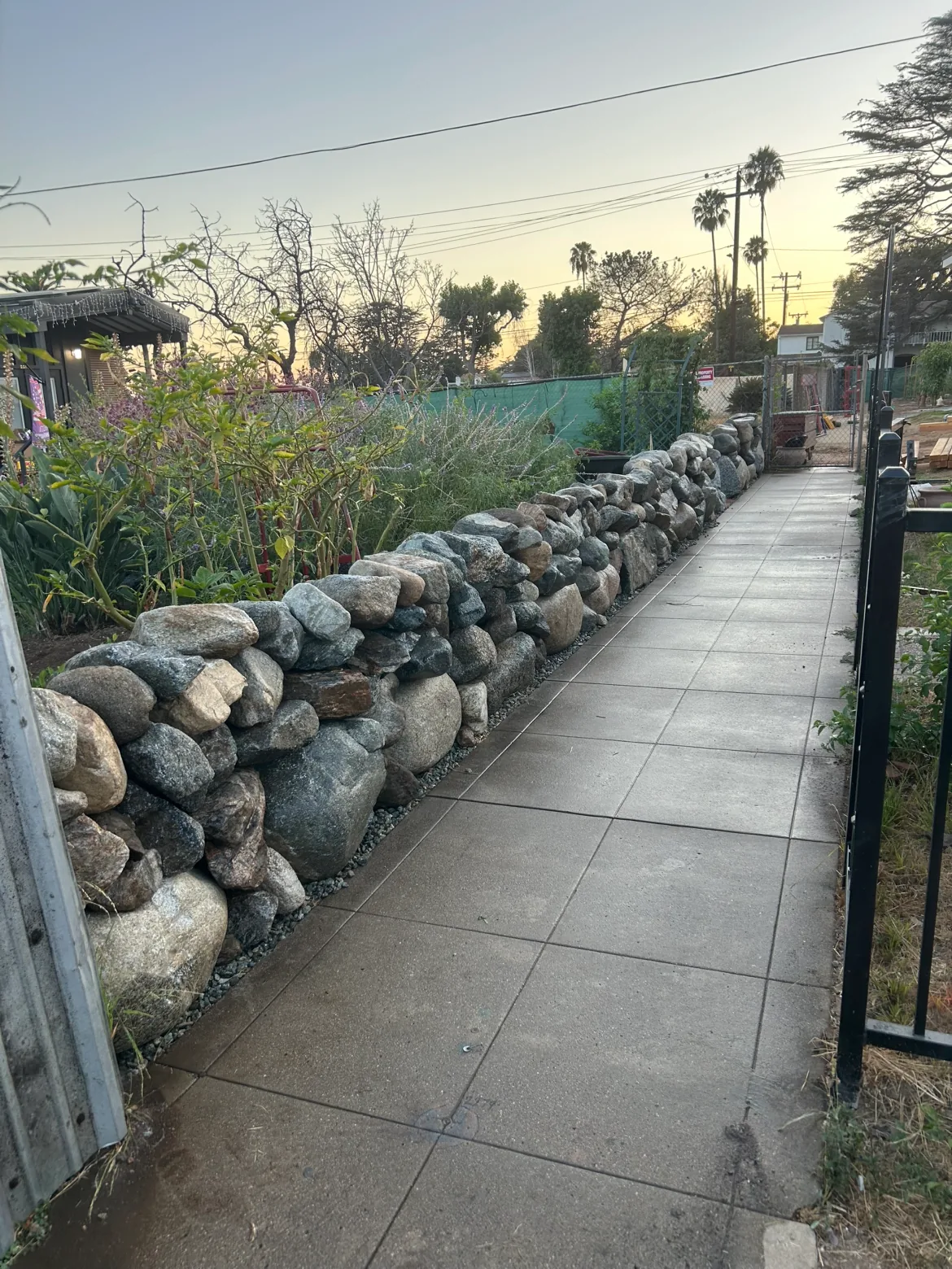 River rock retaining wall beside a new concrete walkway