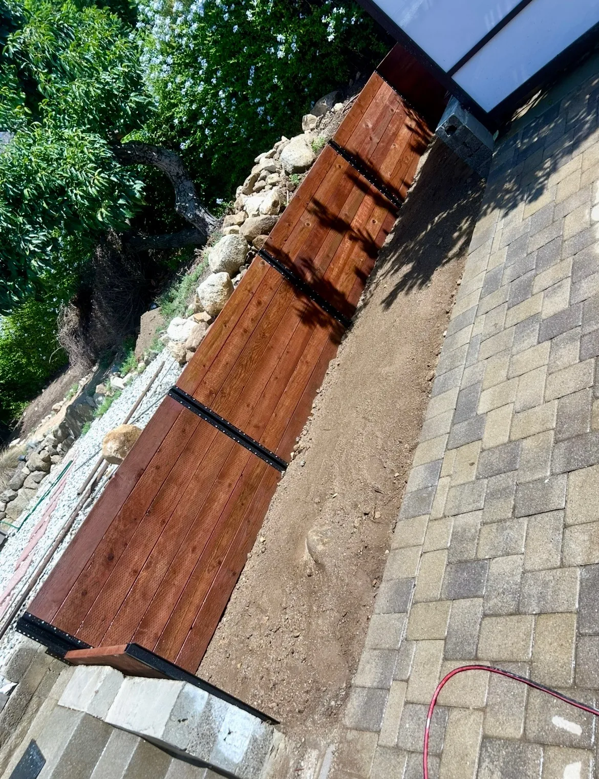 Paver walkway beside a wood-capped retaining wall