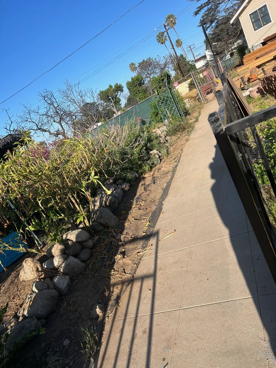 Narrow side yard with a rough dirt path and loose rock along the slope